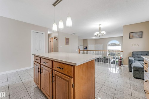 Kitchen island featuring wood cabinetry with dark hardware, a light-toned countertop, and pendant lighting overhead - 1529 49A Street Nw, Edmonton, AB - Indoor