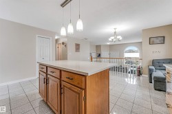 Kitchen island featuring wood cabinetry with dark hardware, a light-toned countertop, and pendant lighting overhead - 