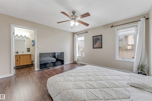 Spacious room featuring wood-finish flooring, two windows with blinds, and an overhead ceiling fan with integrated lighting - 1529 49A Street Nw, Edmonton, AB - Indoor Photo Showing Bedroom