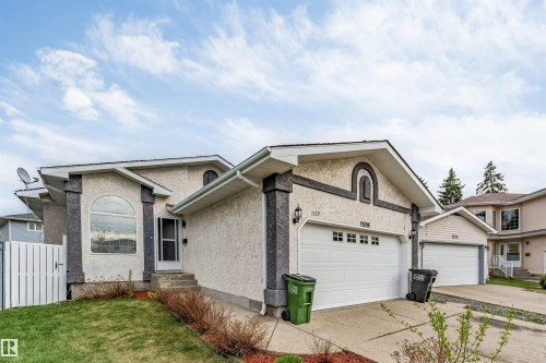 Stucco exterior with decorative stone accents, arched window, and attached double garage - 1529 49A Street Nw, Edmonton, AB - Outdoor