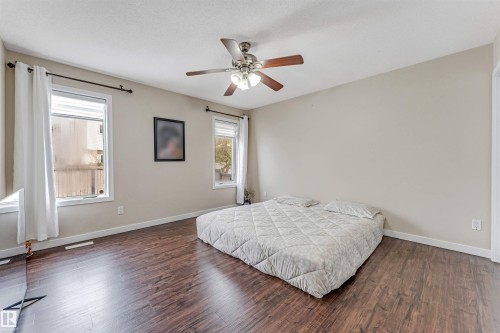 Spacious room featuring rich wood-finish flooring, neutral wall tones, and a ceiling fan with integrated lighting - 1529 49A Street Nw, Edmonton, AB - Indoor Photo Showing Bedroom