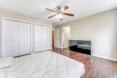 Bedroom with wood-finish flooring, two sets of bi-fold closet doors, and a ceiling fan with integrated lighting - 1529 49A Street Nw, Edmonton, AB - Indoor Photo Showing Bedroom