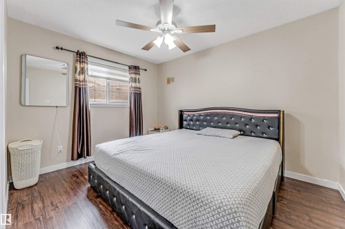 Spacious room featuring wood-finish flooring, a window with horizontal blinds, and a ceiling fan with integrated lighting - 1529 49A Street Nw, Edmonton, AB - Indoor Photo Showing Bedroom