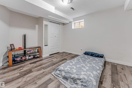 Spacious room featuring wood-finish flooring, white baseboards, and a white ceiling - 1529 49A Street Nw, Edmonton, AB - Indoor Photo Showing Bedroom