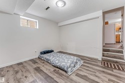 Spacious room featuring wood-finish flooring, a white ceiling with a flush-mount light fixture, and a high window with grilles - 