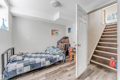 Room featuring wood-finish flooring, light grey painted walls, a textured ceiling, and a high-set window - 1529 49A Street Nw, Edmonton, AB - Indoor Photo Showing Bedroom