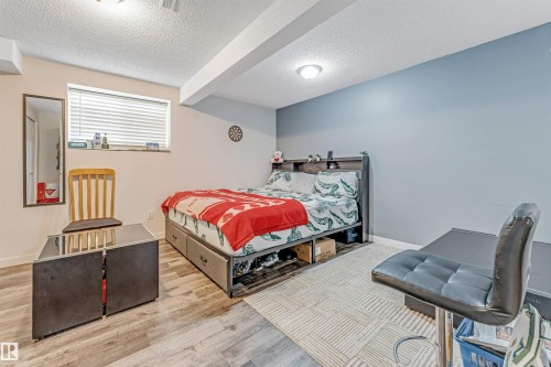 Spacious room featuring light wood-finish flooring, a neutral wall color with an accent wall, and a recessed window with blinds - 1529 49A Street Nw, Edmonton, AB - Indoor Photo Showing Bedroom