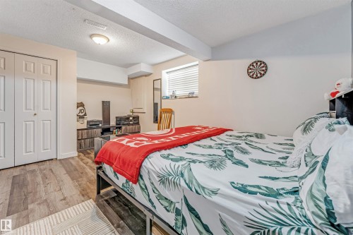 Bedroom featuring wood-finish flooring, a two-panel bifold closet door, and a recessed window with blinds - 1529 49A Street Nw, Edmonton, AB - Indoor Photo Showing Bedroom