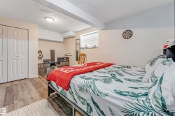 Bedroom featuring wood-finish flooring, a two-panel bifold closet door, and a recessed window with blinds - 