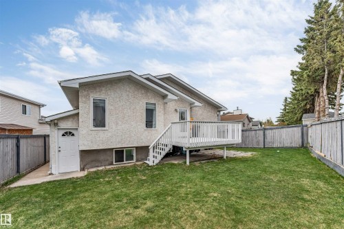 Expansive backyard featuring a manicured lawn, a raised wooden deck with white railing, and a wooden privacy fence - 1529 49A Street Nw, Edmonton, AB - Outdoor With Deck Patio Veranda