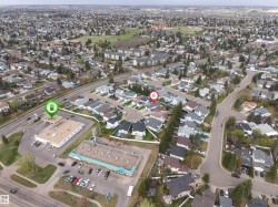 Aerial perspective of a residential neighborhood with a mix of single-family homes and multi-story buildings, featuring mature trees and green spaces - 