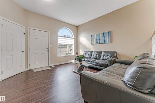 Entry area featuring a paneled door, wood-finish flooring, a vaulted ceiling, and an arched transom window above a rectangular window - 1529 49A Street Nw, Edmonton, AB - Indoor Photo Showing Living Room