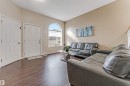 Entry area featuring a paneled door, wood-finish flooring, a vaulted ceiling, and an arched transom window above a rectangular window - 1529 49A Street Nw, Edmonton, AB  - Indoor Photo Showing Living Room 