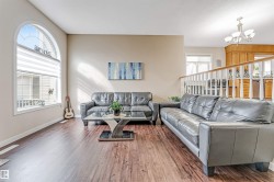 Spacious living area featuring wood-finish flooring, a large arched window with horizontal blinds, and neutral wall tones - 