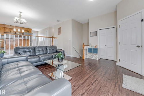 Open-concept living area with dark wood-finish flooring, light neutral wall tones, and a wood and white spindle railing - 1529 49A Street Nw, Edmonton, AB - Indoor Photo Showing Living Room