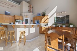 Kitchen and dining area featuring vaulted ceilings, wood cabinetry, a breakfast bar with an integrated countertop, and tiled flooring - 