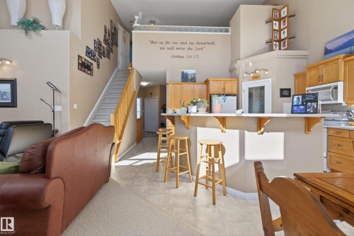 Open-concept living area featuring a kitchen with light wood cabinetry and a breakfast bar - 21 Pipestone Drive, Devon, AB - Indoor Photo Showing Other Room