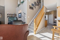 Two-story interior featuring a carpeted staircase with wood railings, a vaulted ceiling, and recessed wall lighting - 