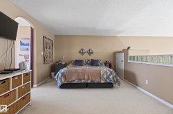 Spacious room with an arched doorway, neutral-toned walls, and soft carpeting - 