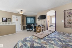 Carpeted room featuring an arched doorway leading to a space with a built-in tub, a wall-mounted light fixture, and a window with blinds - 