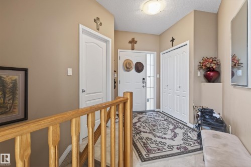 Entryway featuring a light wood-finish banister, a white paneled door, and a white bi-fold closet door - 21 Pipestone Drive, Devon, AB - Indoor Photo Showing Other Room
