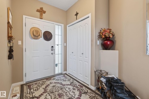 Entryway featuring a white paneled door with sidelight, bi-fold closet doors, and neutral wall tones - 21 Pipestone Drive, Devon, AB - Indoor Photo Showing Other Room