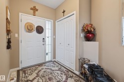 Entryway featuring a white paneled door with sidelight, bi-fold closet doors, and neutral wall tones - 