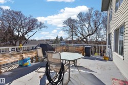 Spacious outdoor deck featuring a white railing system, light-colored siding, and visible mature trees - 