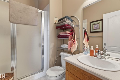 Contemporary bathroom featuring a frosted glass shower enclosure, a white toilet, and a vanity with a white countertop and integrated sink - 21 Pipestone Drive, Devon, AB - Indoor Photo Showing Bathroom