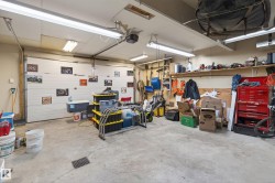 Spacious garage featuring a concrete floor, overhead fluorescent lighting, and a white panel garage door - 