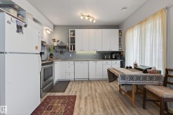Kitchen featuring white cabinetry, light-toned wood-finish flooring, light gray walls, a stainless steel range, and a window with sheer drapes - 