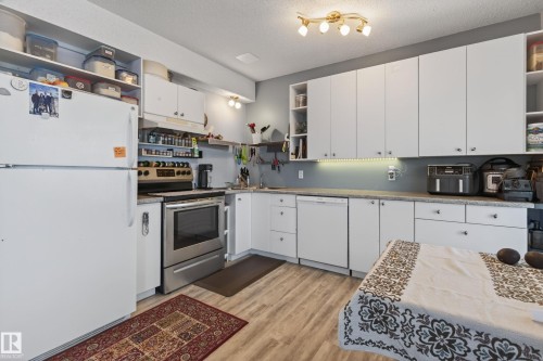 Kitchen featuring wood-finish flooring, white cabinetry, a stainless steel range, and a white dishwasher - 21 Pipestone Drive, Devon, AB - Indoor Photo Showing Kitchen