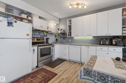 Kitchen featuring wood-finish flooring, white cabinetry, a stainless steel range, and a white dishwasher - 