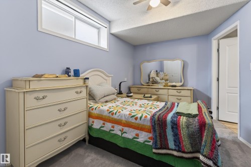 Bedroom featuring light blue walls, gray carpet flooring, a white window trim, a white interior door, and a ceiling fan - 21 Pipestone Drive, Devon, AB - Indoor Photo Showing Bedroom