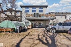 Rear elevation featuring a raised deck with metal railings, ground-level access, and a large arched window design - 
