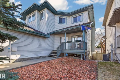 Two-story property featuring light-colored siding, a dark-colored roof, and a covered front porch with railings - 21 Pipestone Drive, Devon, AB - Outdoor With Deck Patio Veranda
