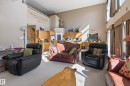 Open-concept living area with vaulted ceilings, large windows with vertical blinds, light-toned carpeting, and a built-in kitchen pass-through with wood cabinetry - 21 Pipestone Drive, Devon, AB  - Indoor 
