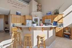Kitchen featuring wood-finish cabinetry, a peninsula with a breakfast bar, white countertops, and light-colored flooring - 