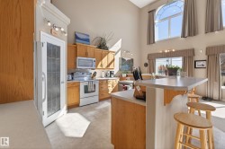Kitchen featuring light wood cabinetry, white appliances, and a central island with an extended countertop - 