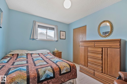 Carpeted bedroom with a single window, overhead flush mount lighting, and a wood-finish closet door - 4707 10A Avenue, Edmonton, AB 