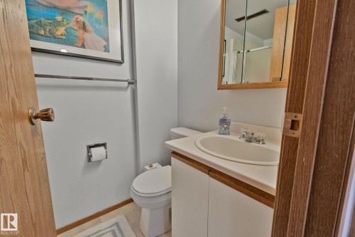 Bathroom featuring a vanity with an integrated sink, laminate countertop, and wood-finish cabinetry - 4707 10A Avenue, Edmonton, AB 