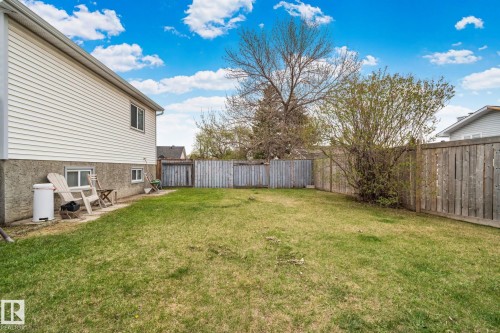 Expansive grass lawn featuring a wood perimeter fence and mature trees - 4707 10A Avenue, Edmonton, AB 