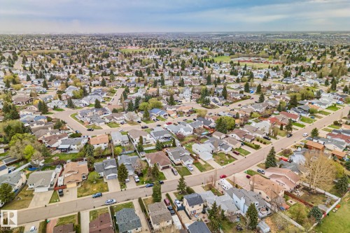 Expansive aerial perspective showcasing a residential neighborhood with numerous single-family homes, mature trees, and a network of paved streets - 4707 10A Avenue, Edmonton, AB 