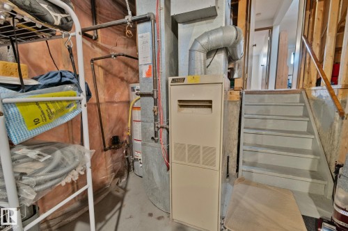 Utility area featuring a water heater, furnace, exposed ductwork, and unfinished wood framing - 4707 10A Avenue, Edmonton, AB 