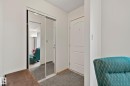 Entryway with a white paneled door, mirrored sliding closet doors, and gray carpet flooring - 4707 10A Avenue, Edmonton, AB 