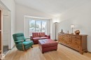 Bright living area featuring multiple windows, wood-finish flooring, white walls, and a vaulted ceiling - 4707 10A Avenue, Edmonton, AB 