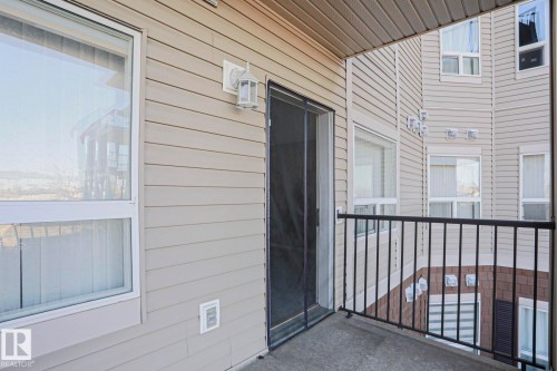 Balcony with concrete flooring, black metal railings, and a sliding screen door - 201 1520 Hammond Gate Gate, Edmonton, AB 