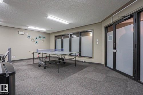 Recreation space featuring patterned carpet flooring, recessed lighting, large frosted windows, and a glass-paneled entry door - 201 1520 Hammond Gate Gate, Edmonton, AB 