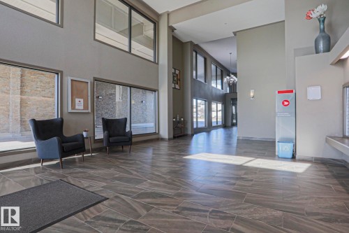 Spacious entry foyer featuring large format tile flooring, extensive window placements, and recessed lighting - 201 1520 Hammond Gate Gate, Edmonton, AB 