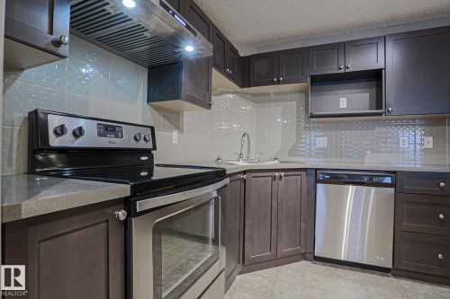Modern kitchen with dark wood-finish cabinetry, gray countertops, and a tiled backsplash - 201 1520 Hammond Gate Gate, Edmonton, AB 